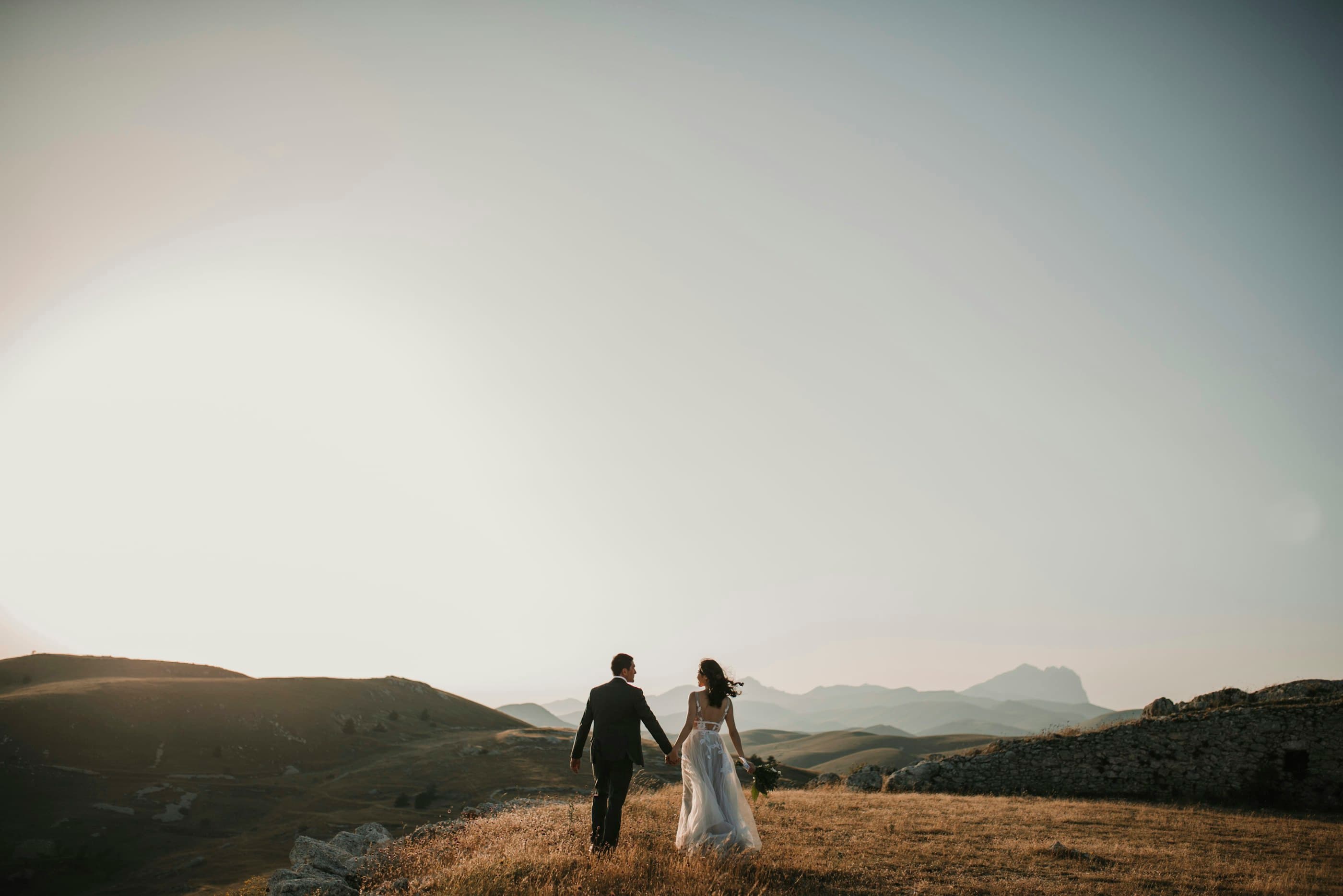 Couple walking through hills at sunset